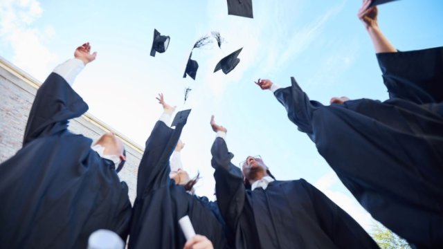 Graduates celebrating by throwing hats into air
