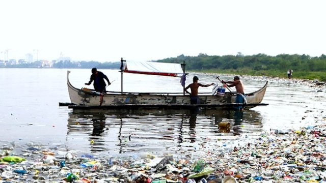 Boat collecting plastic waste in bay