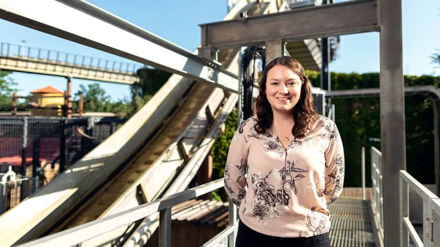 Michelle, a civil engineer, stands in front of a rollercoaster