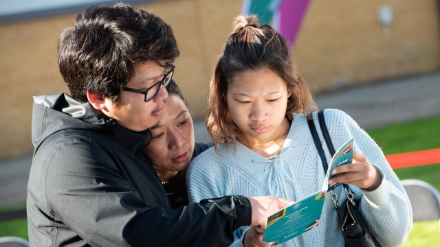 Parents and young person at open day looking at a programme