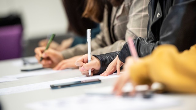 Students' hands writing in the classroom