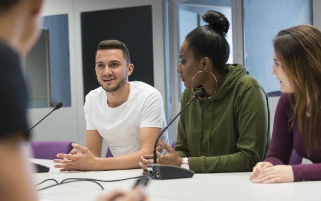 Four students around a desk talking