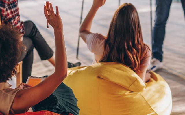 People sitting on bean bags with hands raised.