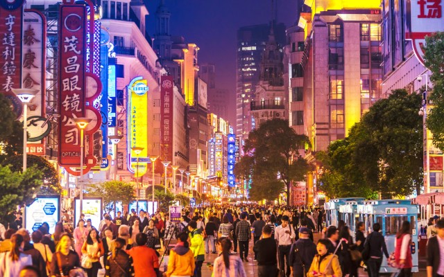 A city at night lit up with lots of people walking around