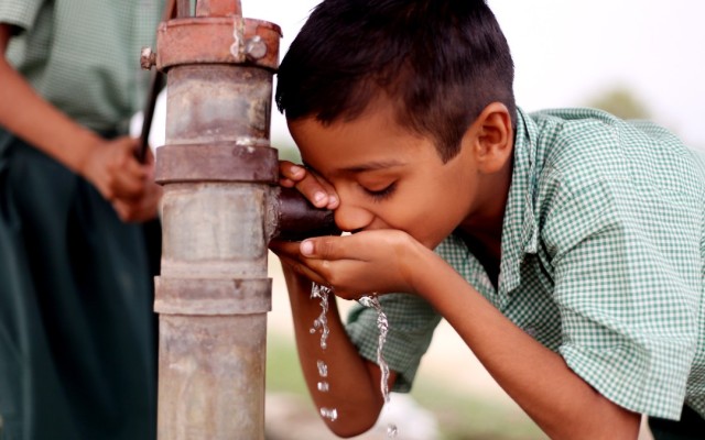 Boy drinking water from a pump