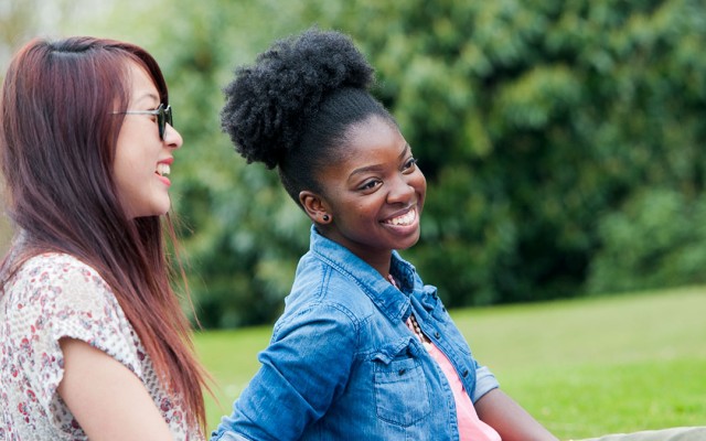 Students sat on grass laughing together