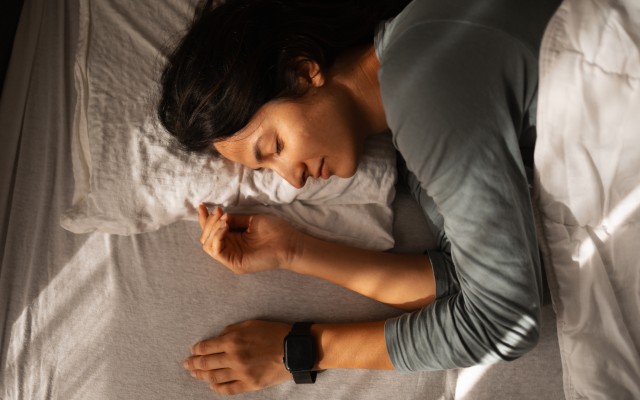woman sleeping peacefully in bed with a smartwatch on her wrist