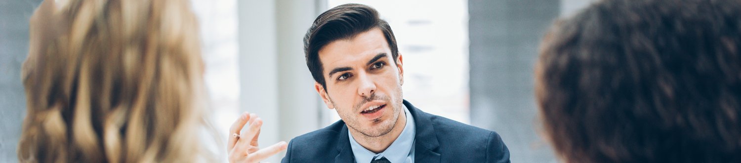 Male in suit talking to two colleagues