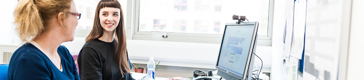 Two people sitting by a computer having a chat