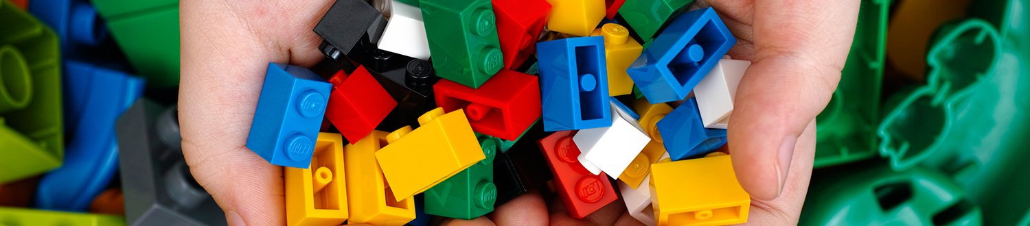 A pair of cupped hands holding lots of different coloured Lego bricks