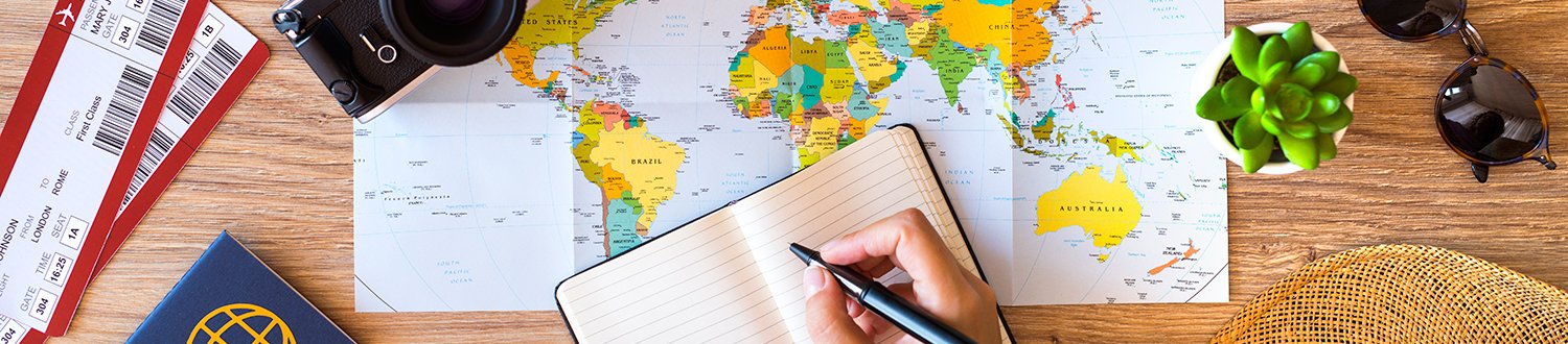 Somebody is writing in a note book that is sitting on an open world map