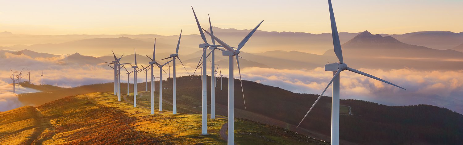 Wind turbines on top of a hill at sunset