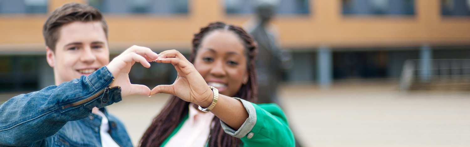 Two students are making a heart with their hands