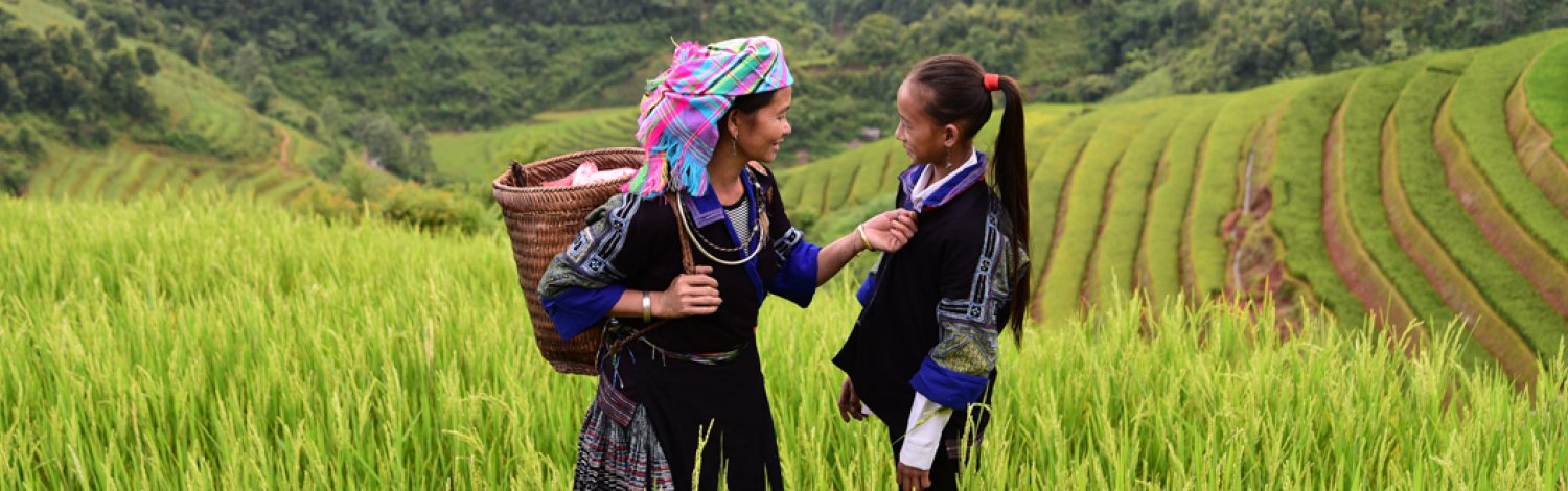 Two women talking with green fields surrounding them