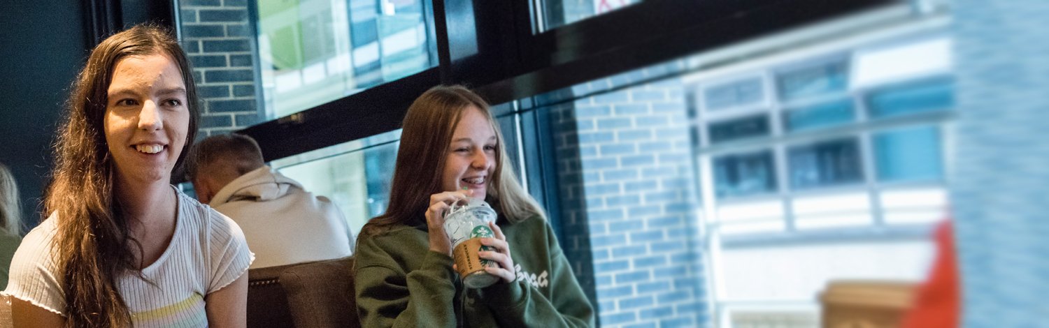 Two students in Starbucks smiling