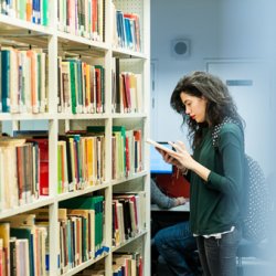 Female student browsing books in the University of Surrey library