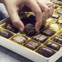Person picking up a chocolate from a tray
