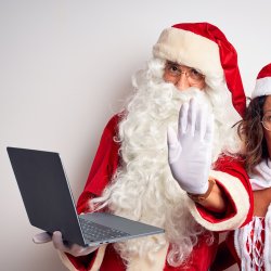 Santa holding a laptop making a stop signal with his hand