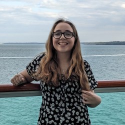 Cat is smiling at the camera with the sea behind her.