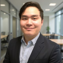 A man in a suit smiling in an office setting.