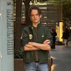 Zac standing with his arms crossed, looking at the camera