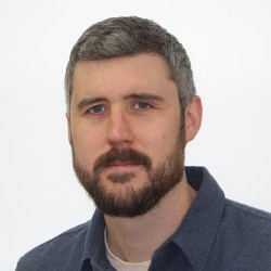 Portrait photo of Matt Glover. He has dark hair, with grey and a beard.