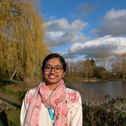 Student smiling on a bright day next to the University lake 