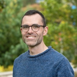 Image of man in blue jumper with spectacles smiling