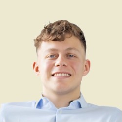 Male student smiling against a beige background