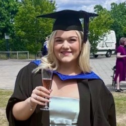 Digital Marketing MSc University of Surrey student, Rebecca, in her graduation robes holding a glass of fizz