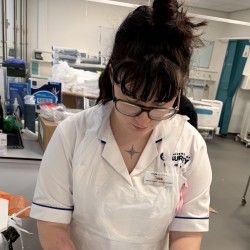 Rose is practising her skills in the ward, wearing her Surrey nursing uniform.