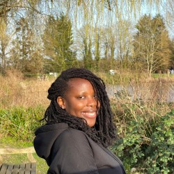 Eunice, am Astronautics and Space Engineering student, looking over her shoulder by the lake on Surrey's campus.