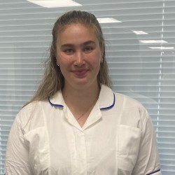 Jess wears a nursing uniform and smiles at the camera.