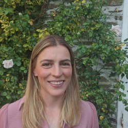 Image of Jessica Day, Biomedical Engineering graduate, smiling in front of some foliage. 