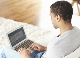 Man working on his laptop at home on the sofa
