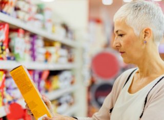 Lady reading health information on a packet of food in the supermarket