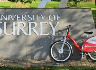 Red Santander bike in front of the University of Surrey stag statue