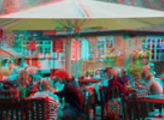 People seated at a table under a parasol by a river