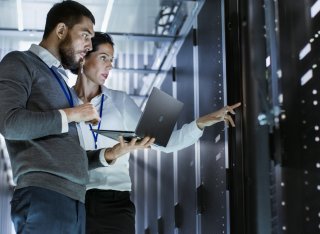 Two people standing in front of a computer server