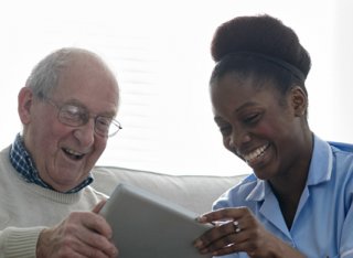 Elderly man using a tablet alongside nurse