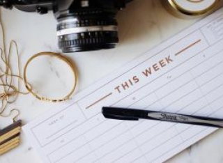 Weekly planner on desk next to camera