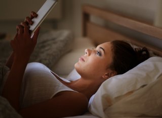 Female in bed using tablet