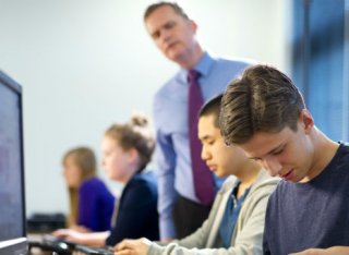 Students and teacher working in front of computers