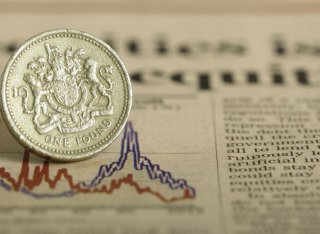 A pound coin sits on a financial newspaper