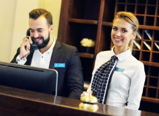 A male and female reception worker working together in a hotel