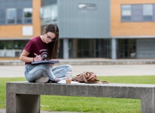 Student sitting on bench reading