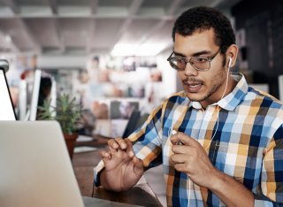 Male talking into headphones looking at laptop