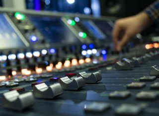 A hand navigates a sound mixing desk