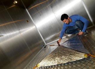 A male student working on satellite technology for space.