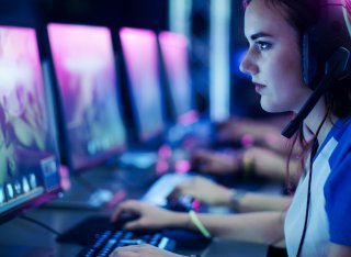 Girl playing video games on a computer wearing a headset